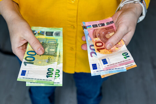 Person holding euro banknotes in both hands separating money into two stacks. Cash management budgeting income and spending concept with European currency.