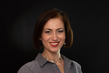 Fototapeta premium Portrait of a mature woman with an open gaze against a dark background.