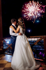 A newlywed couple watches a wedding fireworks display against