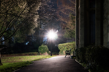A bench and park next to Victorian gothic building. converted into offices on a winters night. Malvern UK
