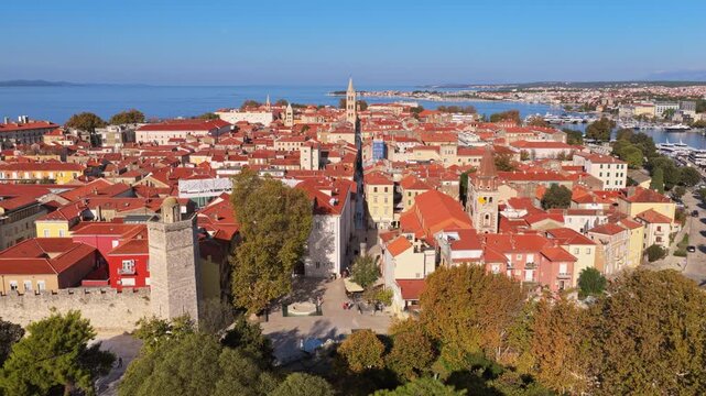 Aerial drone view of the Zadar Old Town with its dense red roofed buildings, medieval towers, narrow stone streets and the Adriatic Sea in the background