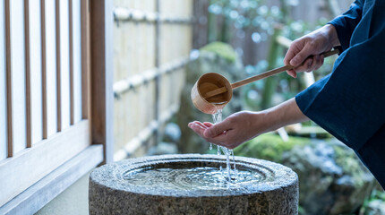 神社の手水舎で柄杓を持ち手を清める参拝者の手元、伝統的な清めの作法