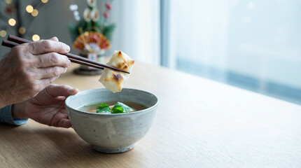 箸で焼き餅を持つ手とお雑煮、日本の正月料理と伝統的な新年の食文化