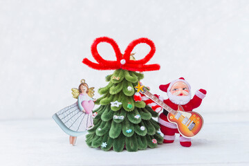 Santa Claus and his guitar with angel holding pink heart and Christmas tree on white background, Happy Christmas party, greeting card background idea