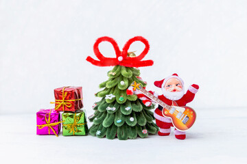 Santa Claus with his guitar and Christmas tree with gift box on white background, Christmas card background idea