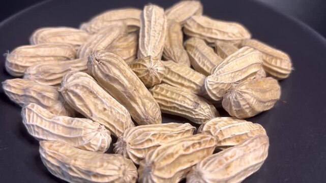 A bunch of peanuts. The peanuts are in the middle of the pile. The peanut is rotates.