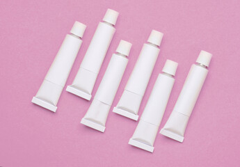 Set of white empty tubes of acrylic or oil paint for creativity on pink background. Template for design, mockup