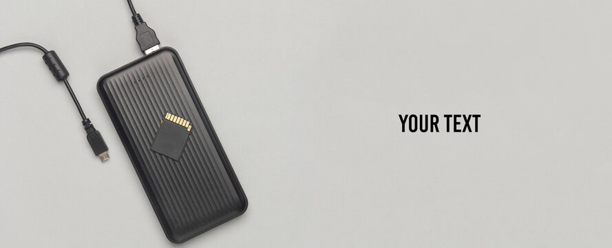 External hard drive with memory card on gray background with copy space