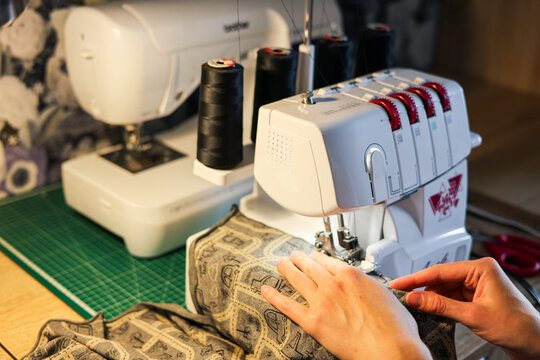 Sewing workshop. sewing machine and woman's hands. Stitching on sewing machine, overlocking. Stitch and overlock. Sewing and stitching at home, tailoring clothes at home.
