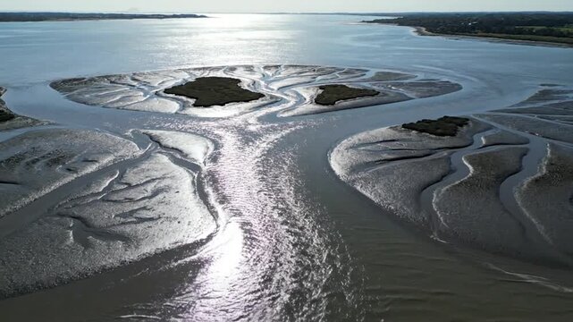 Aerial view of a tidal mudflat with winding water channels and small islands