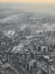 Panoramic aerial view of winter city with snowy rooftops and roads at sunrise.