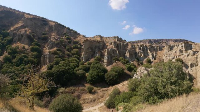 A breathtaking view of Kula fairy chimneys  by vibrant greenery under a bright sky, depicting nature's wild beauty and the awe-inspiring formations of the earth.
