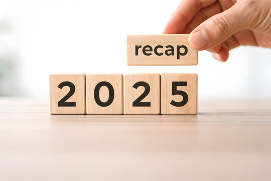Hand placing wooden block with recap text next to blocks showing 2025 on a wooden table, concept of annual review or looking back at the year