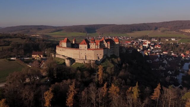 Aerial drone panorama of Burg Harburg on its elevated ridge near the Woernitz River in Donau Ries, Bavaria, Germany during golden hour in chilly weather.