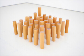 Wooden isometric design group of cylinders of different heights in grid on white floor