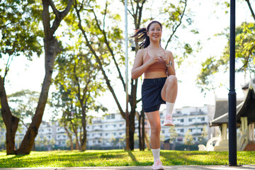 Full body length of young Asian woman doing workout training outside, warming up and jumping up high, lady in sportswear enjoying outdoors training