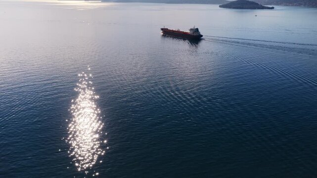 Aerial drone view of an oil tanker traveling across open Adriatic waters with distant mountain ridges and coastal towns visible on the horizon