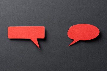 Red blank paper speech bubbles with shadow and copy space for text on dark background, top view...