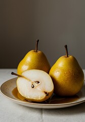 Three yellow pears on a plate with one sliced half for food and product visuals