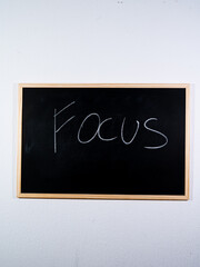 Chalkboard showing FOCUS concept written vertically representing mental clarity, discipline and goal orientation