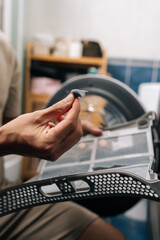 Male hand removing accumulated lint and fibers from tumble dryer filter, highlighting importance of regular cleaning for appliance maintenance and efficient operation.