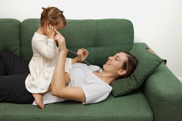 Mother and daughter listening music, sharing headphones, smiling