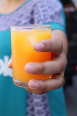 Soft drinks orange juice and iced in glass on hand