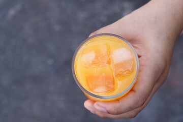 Soft drinks orange juice and iced in glass on hand