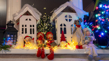 Christmas view from a white cardboard house, various gnome figures, colorful lights, home interior decor, festive mood