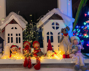 Christmas view from a white cardboard house, various gnome figures, colorful lights, home interior decor, festive mood