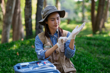 Asian adult botanist researcher preparing for fieldwork science study in natural environment putting on protective gloves with toolkit