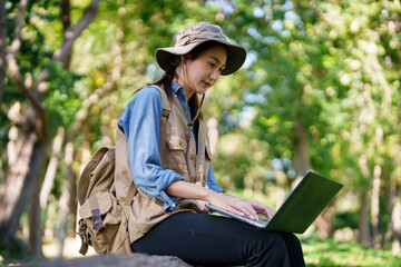 Asian botanical researcher actively conducts field study using laptop computer outdoors exploring green natural environment collecting scientific data plant research