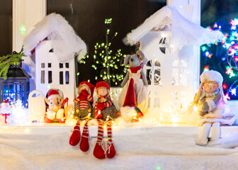 Christmas view from a white cardboard house, various gnome figures, colorful lights, home interior decor, festive mood