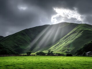Dramatic landscape of sunbeams shining on green hills and pastures, under a cloudy sky