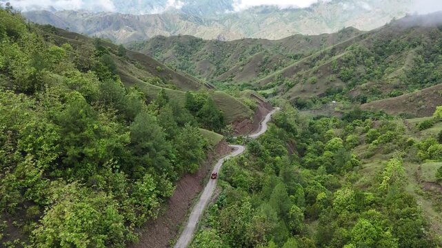 Aerial view of car driving through the fores and the lake on the side. Beautiful mountain road. Driving on the mountain road. Road trip. Mountain forest lake landscape. Car driving through pine forest