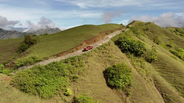 Aerial view of car driving through the fores and the lake on the side. Beautiful mountain road. Driving on the mountain road. Road trip. Mountain forest lake landscape. Car driving through pine forest