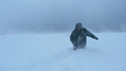 Man braving harsh arctic snowstorm in heavy winter gear under cloudy sky
