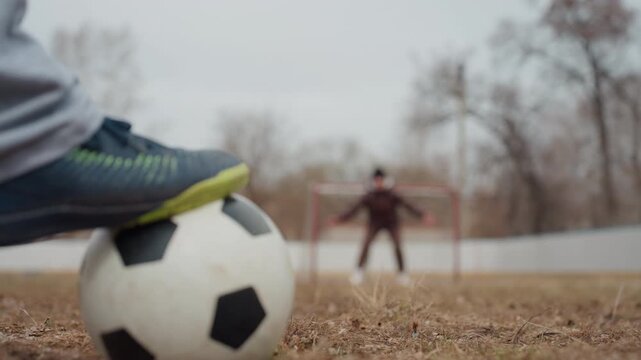 goalkeeper stance anticipation, urban soccer scene with focused goalkeeper, quiet moment before soccer player takes shot, overcast sky and empty trees set tense scene for soccer practice