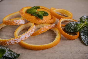 Aromatic Orange Peels with Mint and Powdered Sugar on Wood