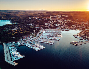 Aerial view of the harbor's gleaming boats and charming coastal architecture bask in the warm glow of the setting sun, Vrsar, Istria County, Croatia.