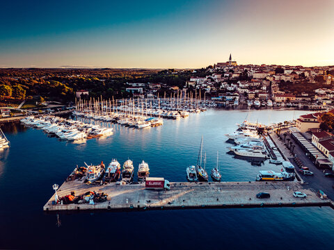 Aerial view of boats nestled in the harbor waters, framed by the historic town on the hill bathed in the glow of the setting sun, Vrsar, Istria County, Croatia.