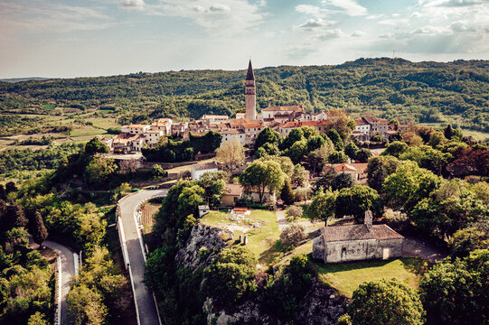 Aerial view of the spire of St. Rocco's Church rises above terracotta rooftops and verdant trees, a picturesque European vista., Pican, Istria County, Croatia.