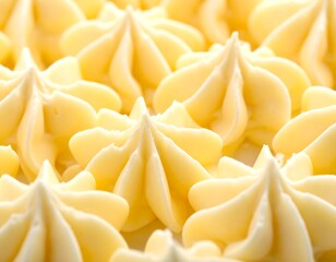 Close up view of rich piped yellow vanilla buttercream frosting swirls on a confectionary surface