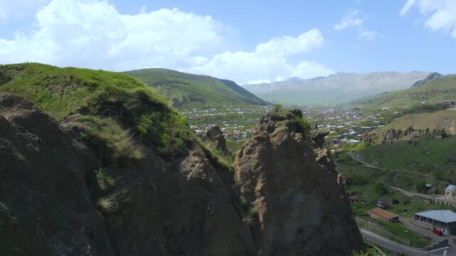 Aerial drone video shows jermuk city in armenia surrounded by rocky cliffs green hills and mountain valley revealing dramatic landscape urban nature harmony travel destination and caucasus scenery