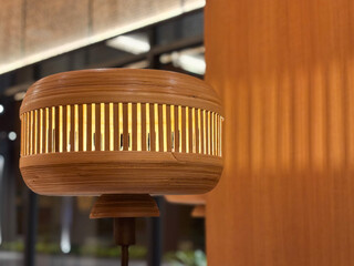 Modern Bamboo Lantern Table Lamp with Warm Ambient Lighting. A beautiful handcrafted wooden or bamboo table lamp featuring a unique cylindrical design with vertical slats. The lamp emits a soft