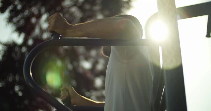 Young athlete performs abs exercise in sunset, street workout, slow motion, middle close up 
