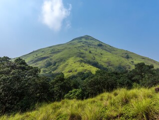 Obraz premium Lush, verdant mountain rising sharply, framed by vibrant greenery and a serene, cloud-speckled sky