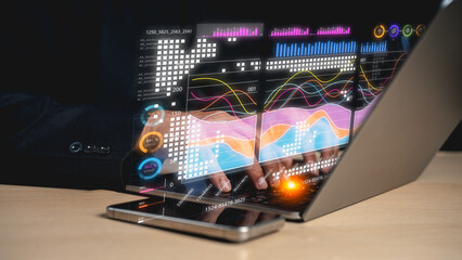 A person interacts with a futuristic holographic display on a laptop, showcasing colorful graphs and data visualization.