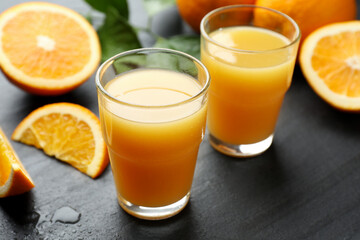Fototapeta premium Fresh orange juice and fruits on black table, closeup