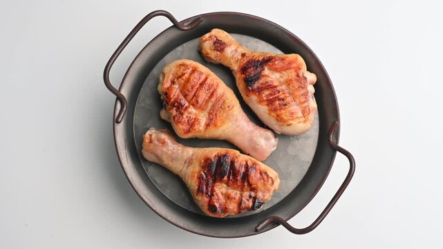 Grilled chicken legs cooked on a barbecue with grill marks shown in a serving dish